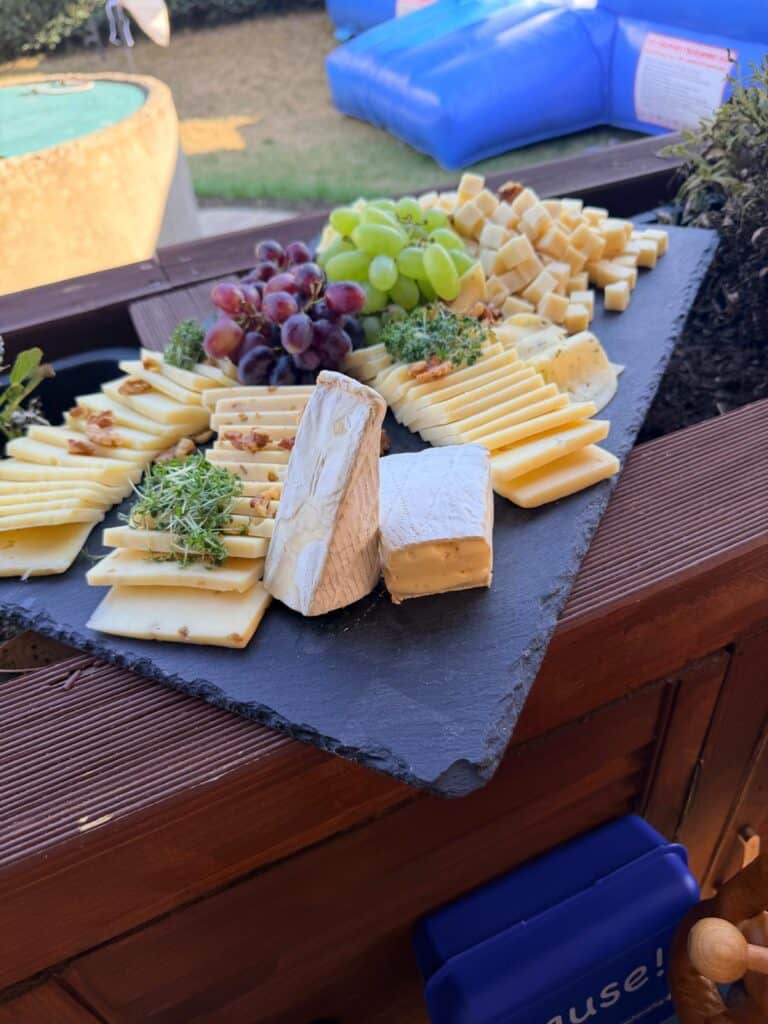 Käseplatte mit Trauben und Brot auf einer Schieferplatte
