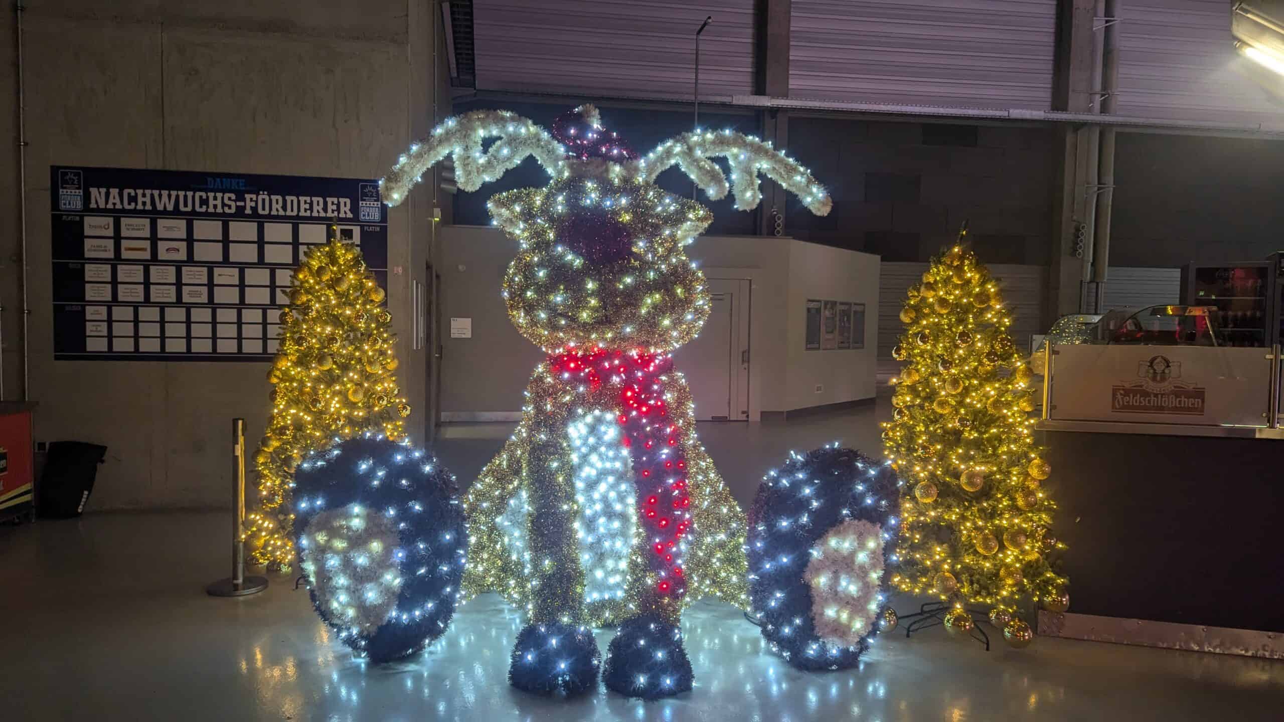 Leuchtende Weihnachtsfiguren und geschmückte Bäume in der Halle
